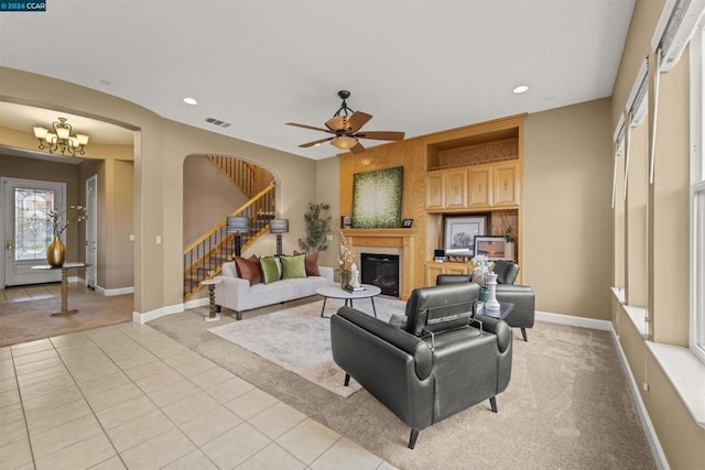 living room with light tile patterned floors and ceiling fan with notable chandelier