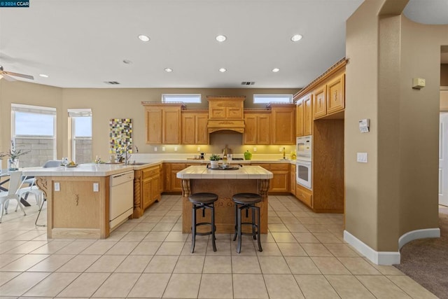 kitchen with a breakfast bar, white appliances, a center island, and kitchen peninsula