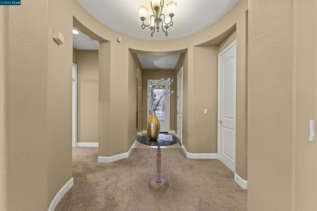 corridor featuring light carpet and a notable chandelier