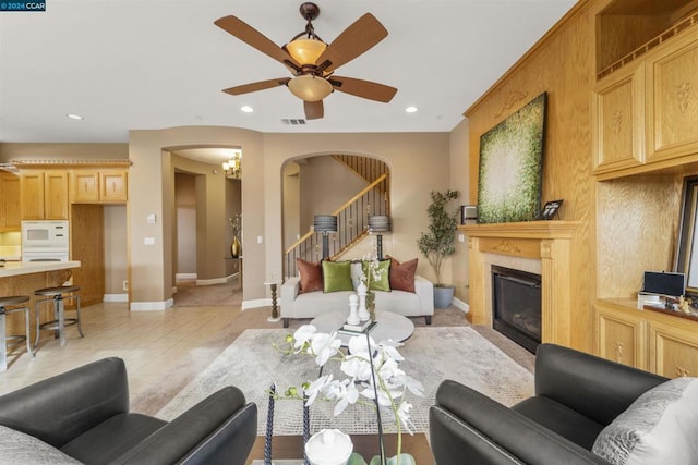 tiled living room with ceiling fan with notable chandelier