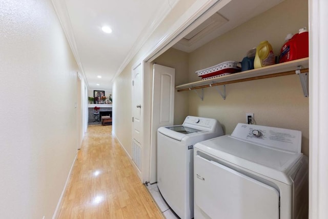 laundry room with washer and dryer, light wood-type flooring, and crown molding