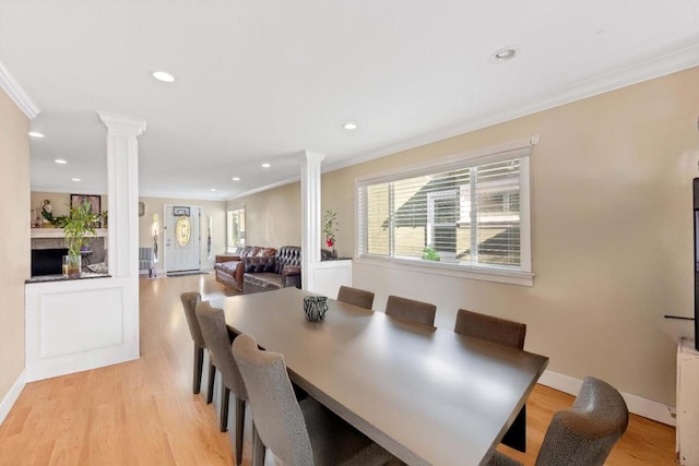 dining room featuring ornamental molding, light hardwood / wood-style floors, and ornate columns