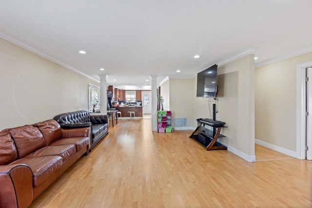 living room with light hardwood / wood-style flooring, crown molding, and ornate columns