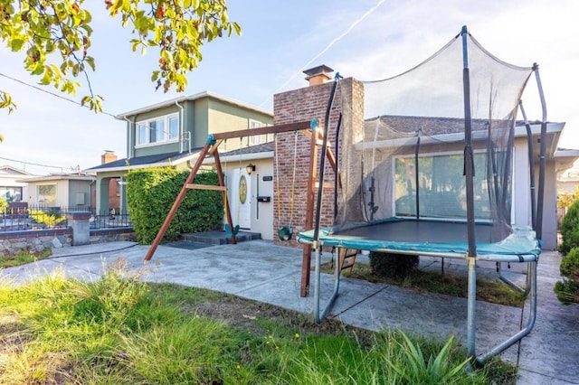 rear view of house with a trampoline and a patio