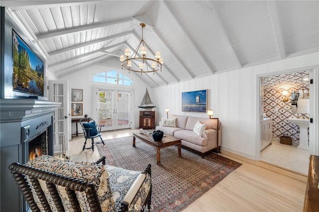 living room featuring a warm lit fireplace, wood finished floors, vaulted ceiling with beams, french doors, and a chandelier