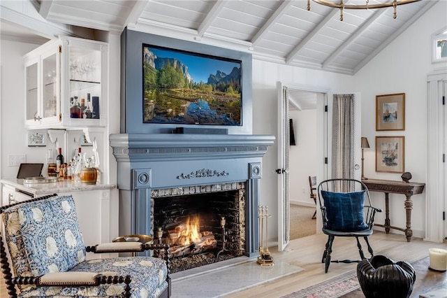 sitting room featuring light wood-style floors, vaulted ceiling with beams, baseboards, and a premium fireplace