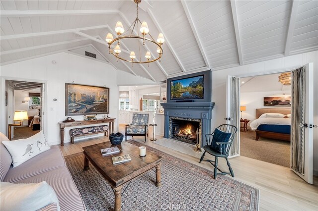 living room featuring light hardwood / wood-style flooring, lofted ceiling with beams, and an inviting chandelier