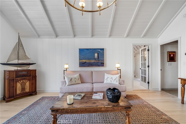 living area featuring lofted ceiling with beams, an inviting chandelier, light wood-type flooring, and baseboards