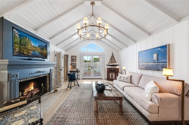 living room with lofted ceiling with beams, french doors, a chandelier, and hardwood / wood-style flooring