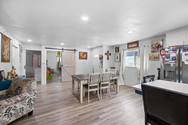 dining area with a barn door and light hardwood / wood-style floors