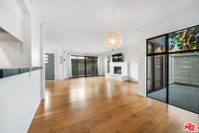 unfurnished living room featuring light wood-type flooring, crown molding, and a healthy amount of sunlight