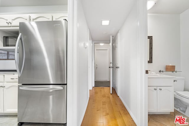 kitchen featuring white cabinets, stainless steel fridge, and light hardwood / wood-style floors