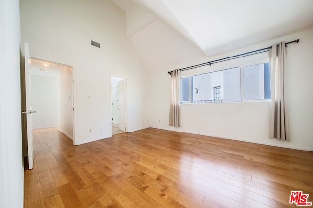 spare room featuring hardwood / wood-style floors and high vaulted ceiling