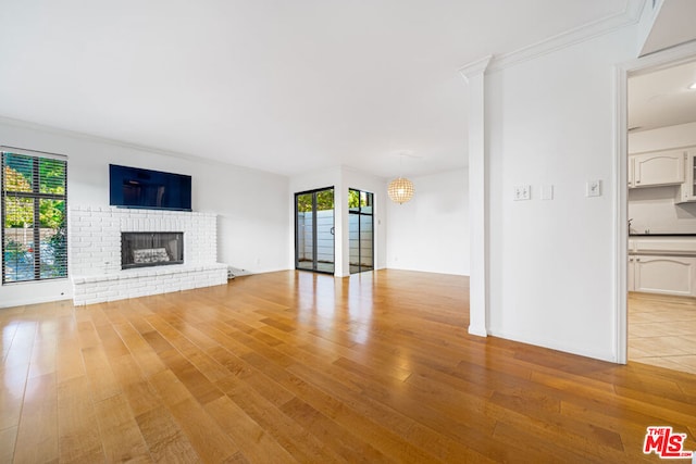 unfurnished living room with a fireplace, light wood-type flooring, and crown molding