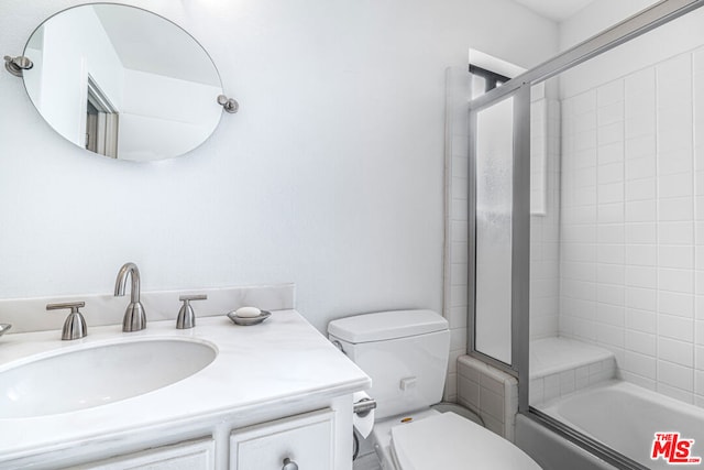 full bathroom with vanity, bath / shower combo with glass door, and toilet