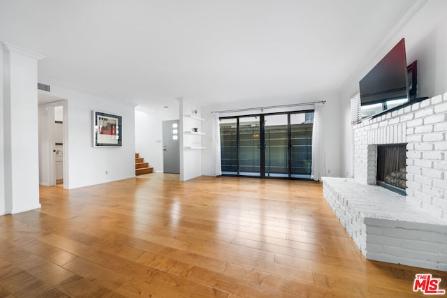 unfurnished living room featuring a fireplace, crown molding, and light hardwood / wood-style flooring