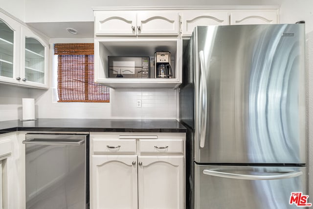 kitchen featuring white cabinets, decorative backsplash, and stainless steel fridge