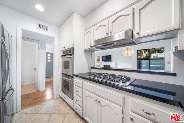 kitchen with white cabinetry, backsplash, and appliances with stainless steel finishes