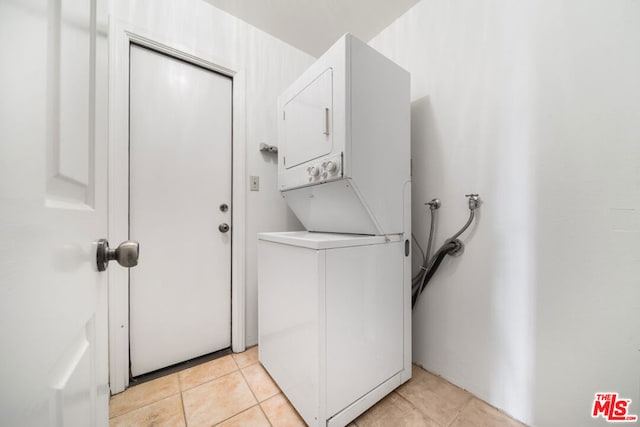 washroom with stacked washer / drying machine and light tile patterned floors