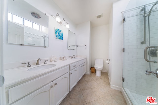 bathroom with tile patterned flooring, vanity, toilet, and a shower with door