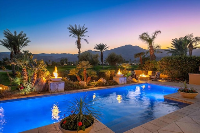 pool at dusk with a mountain view and an outdoor fire pit