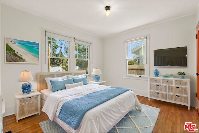 bedroom with hardwood / wood-style floors, multiple windows, and ornamental molding