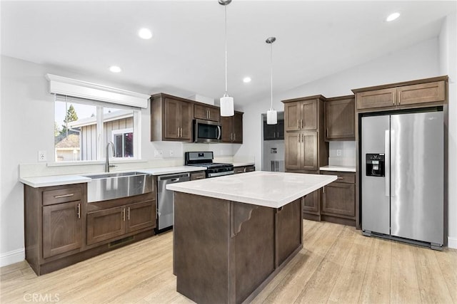 kitchen featuring appliances with stainless steel finishes, sink, decorative light fixtures, light hardwood / wood-style floors, and lofted ceiling