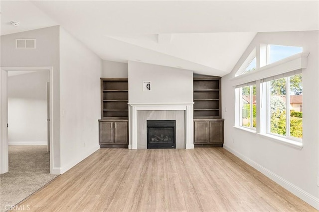 unfurnished living room with a fireplace, light wood-type flooring, and lofted ceiling