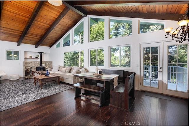 living room with a wood stove, french doors, dark wood-type flooring, high vaulted ceiling, and a notable chandelier