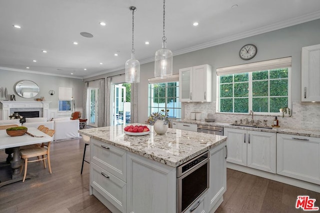 kitchen with sink, wood-type flooring, pendant lighting, a center island, and white cabinetry