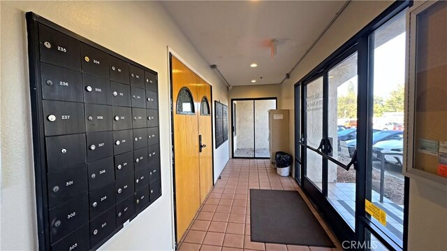 hall featuring light tile patterned flooring and mail area