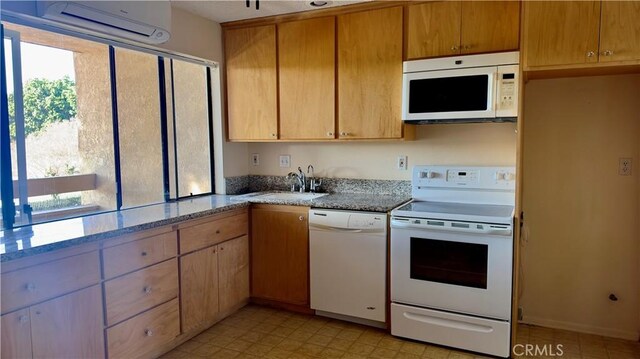 kitchen featuring an AC wall unit, sink, white appliances, and light stone counters