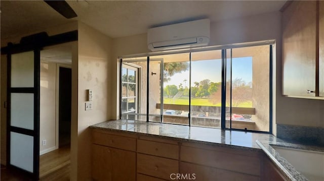 kitchen with a wall unit AC and wood finished floors