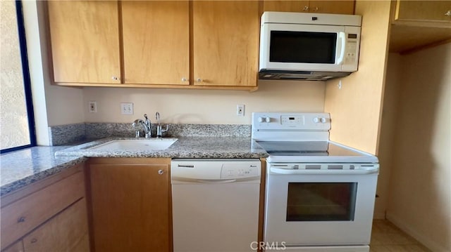 kitchen with light stone countertops, white appliances, and a sink