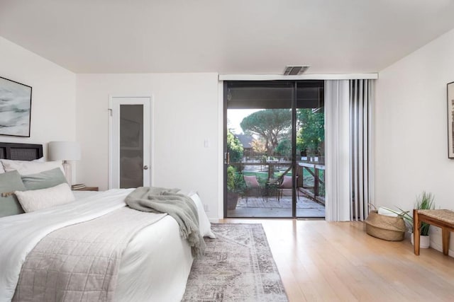 bedroom with floor to ceiling windows, access to exterior, and wood-type flooring