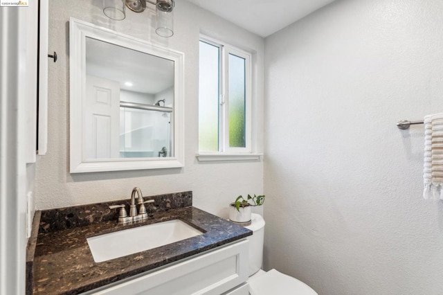 bathroom featuring vanity, toilet, and walk in shower