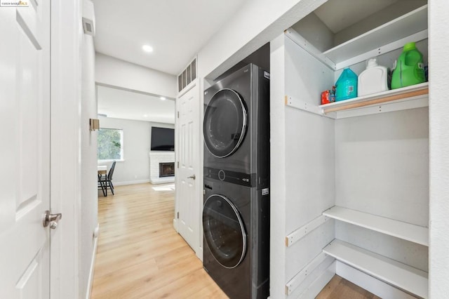 laundry room with stacked washing maching and dryer and hardwood / wood-style floors