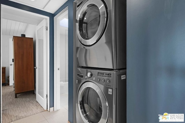 clothes washing area with stacked washing maching and dryer and light tile patterned floors