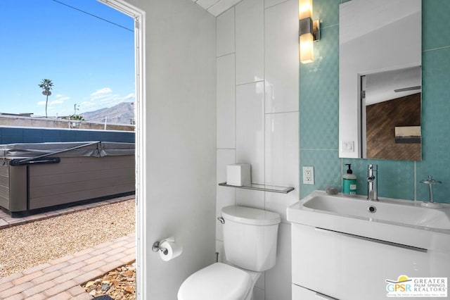 bathroom featuring vanity, toilet, a mountain view, and tile walls