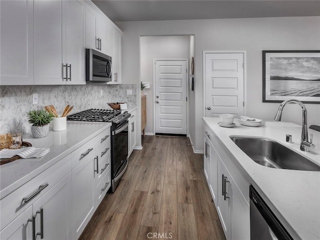 kitchen with white cabinets, sink, decorative backsplash, wood-type flooring, and stainless steel appliances