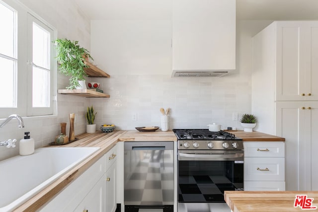 kitchen featuring butcher block counters, white cabinetry, stainless steel appliances, and a wealth of natural light