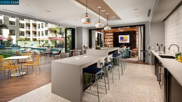 kitchen with a kitchen breakfast bar, decorative light fixtures, light hardwood / wood-style flooring, and sink