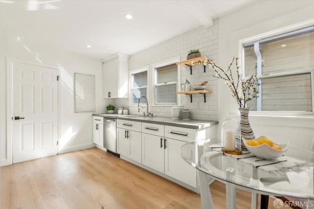 kitchen with white cabinetry, light hardwood / wood-style floors, decorative backsplash, dishwasher, and sink