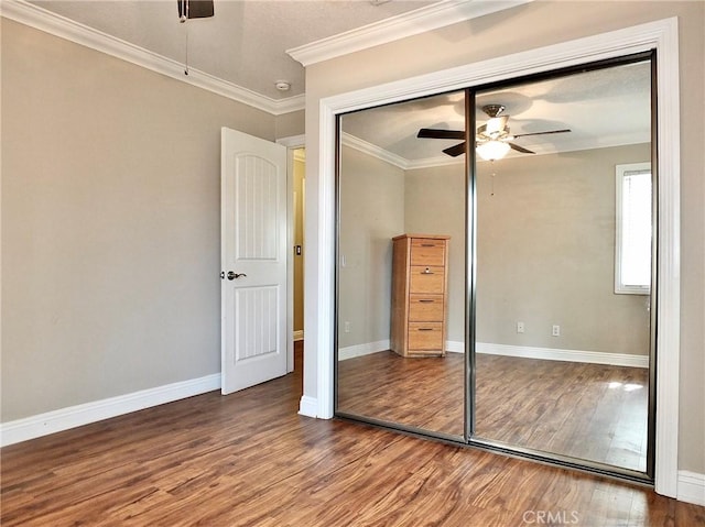 unfurnished bedroom with ceiling fan, a closet, ornamental molding, and hardwood / wood-style flooring