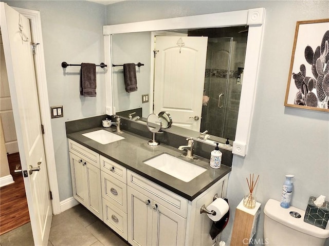 bathroom with tile patterned flooring, vanity, toilet, and a shower with door