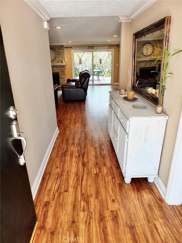 corridor with a textured ceiling, hardwood / wood-style flooring, and crown molding