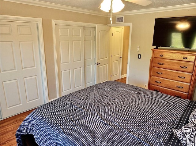 bedroom with hardwood / wood-style floors, crown molding, ceiling fan, a textured ceiling, and a closet