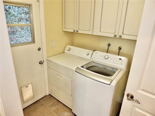 laundry room featuring cabinets, light tile patterned flooring, and washer and dryer