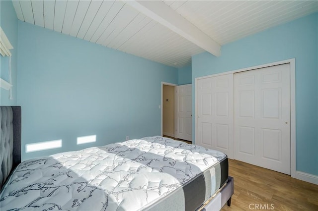 bedroom with beam ceiling, a closet, and hardwood / wood-style floors