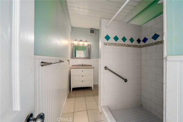 bathroom with a tile shower, vanity, and tile patterned floors